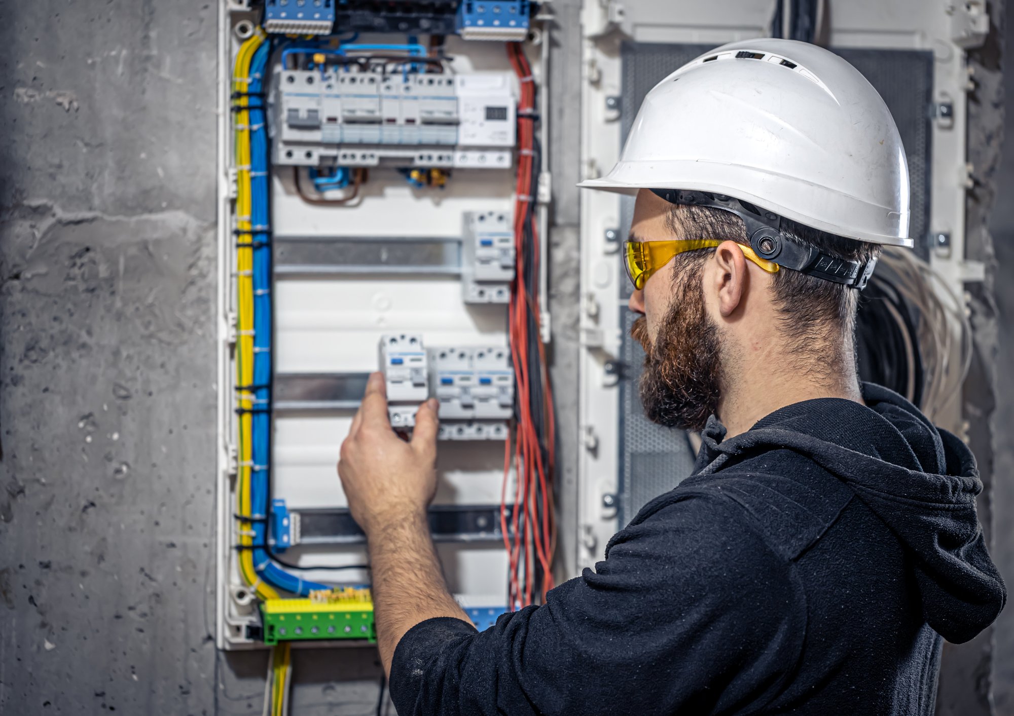 male-electrician-works-switchboard-with-electrical-connecting-cable